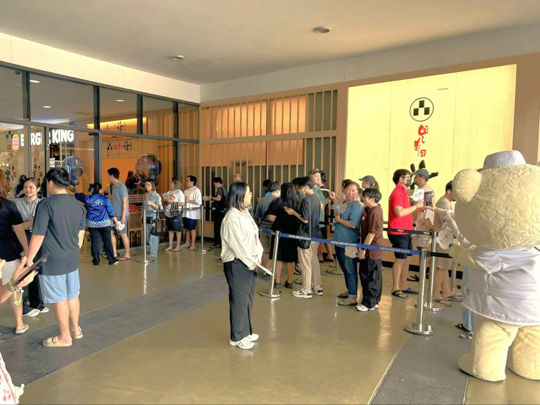 列に並んでいる人々と、マスコットキャラクターが映っている写真